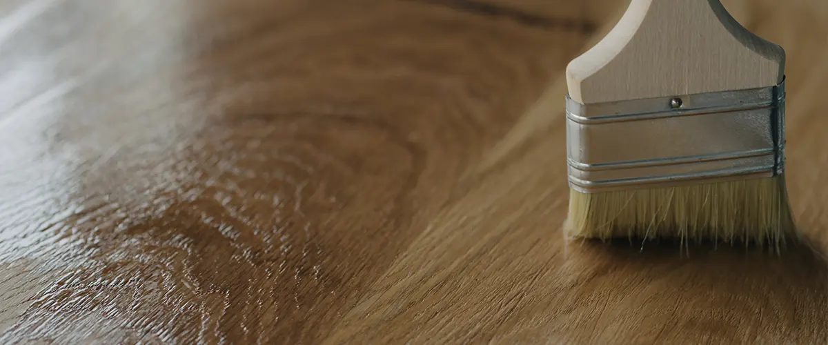 A hardwood floor being finished with a small brush