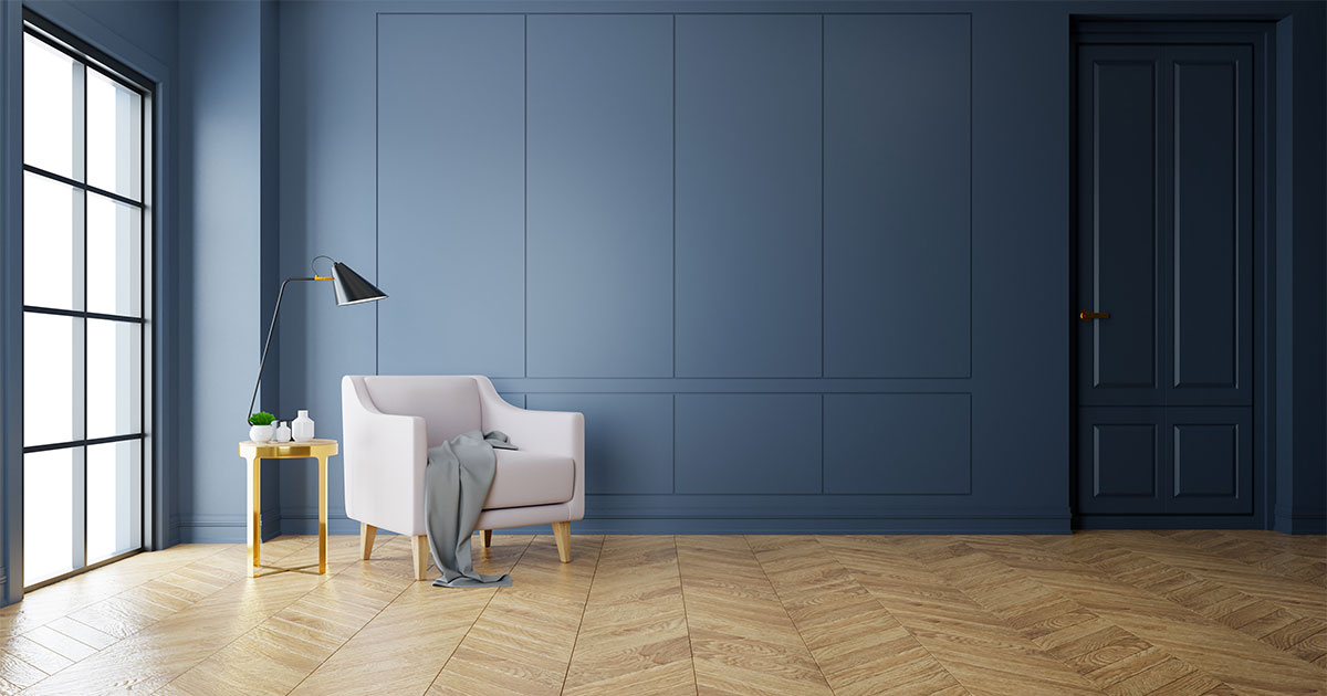 A wood floor with a herringbone pattern in a room with dark blue walls