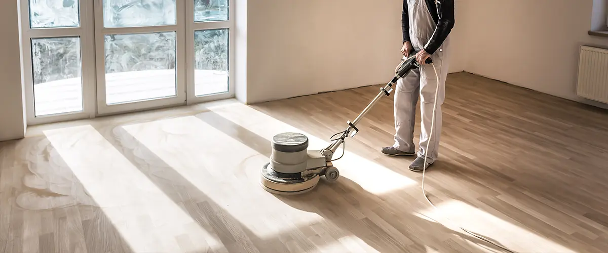 A man with a heavy machine sanding hardwood floors