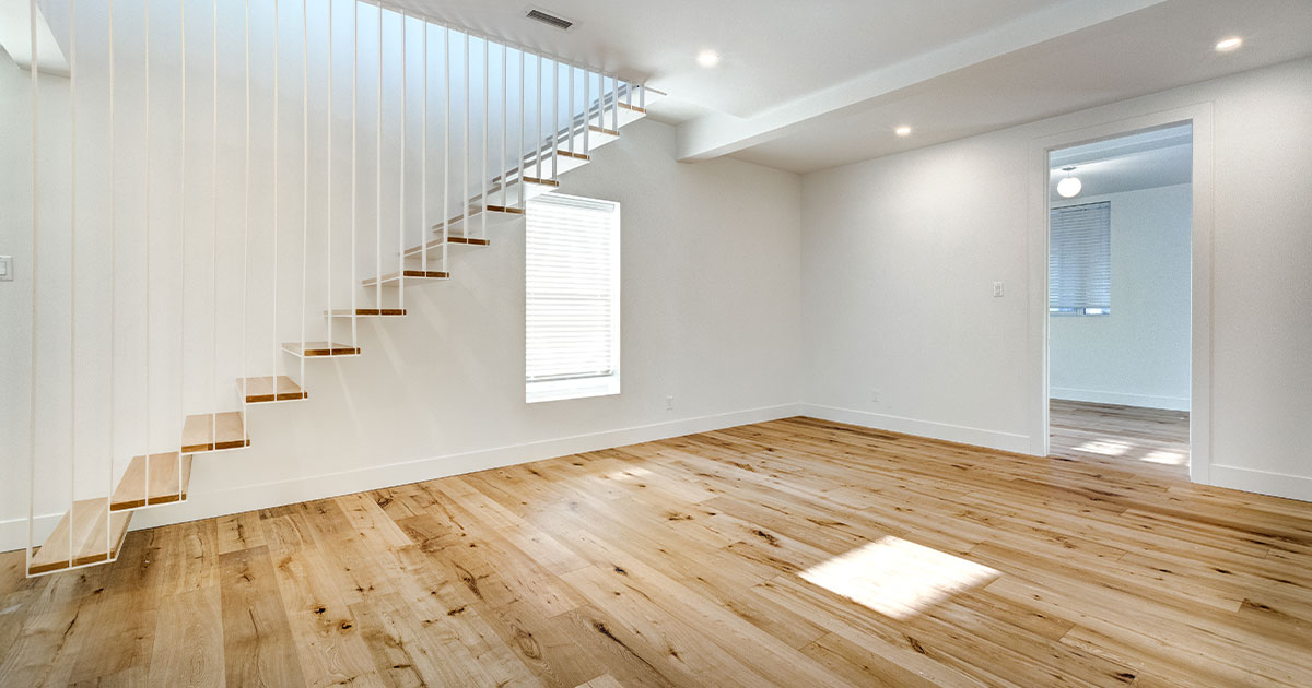 A wood floor in an empty basement with stairs