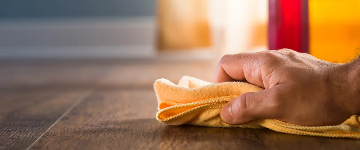 A man staining a wood floor with a rag