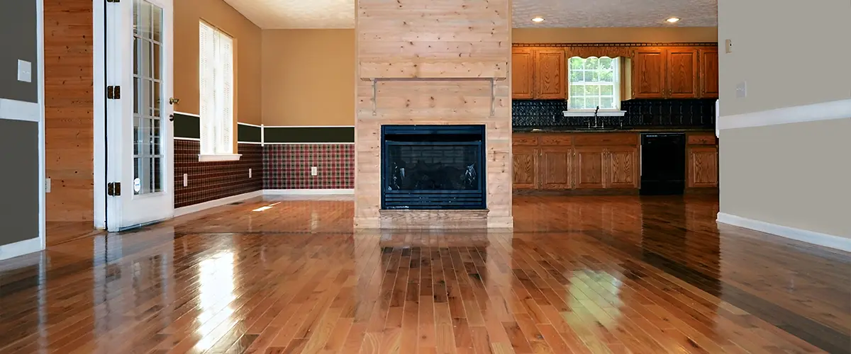 A wood floor with a fireplace in a spacious empty room