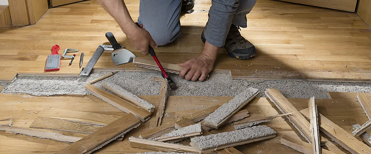 A contractor destroying old wood floorboards