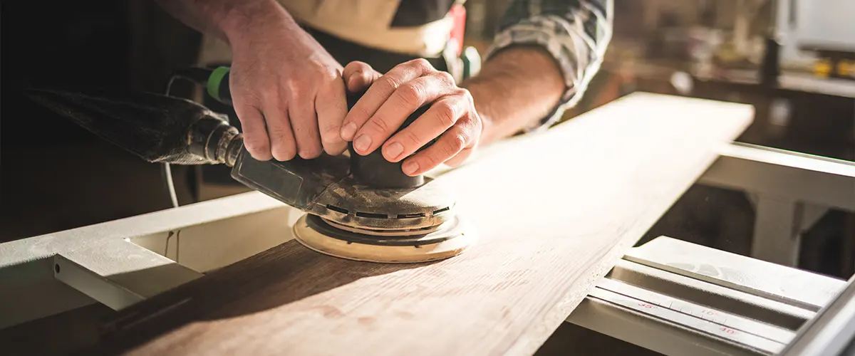 A carpenter sanding a wooden board