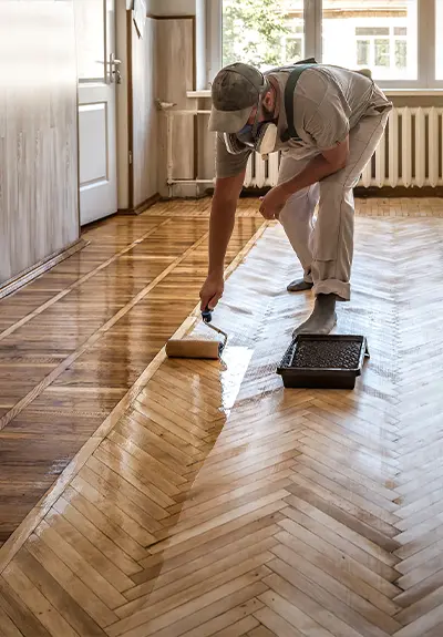 A flooring contractor refinishing a wooden floor in herringbone pattern