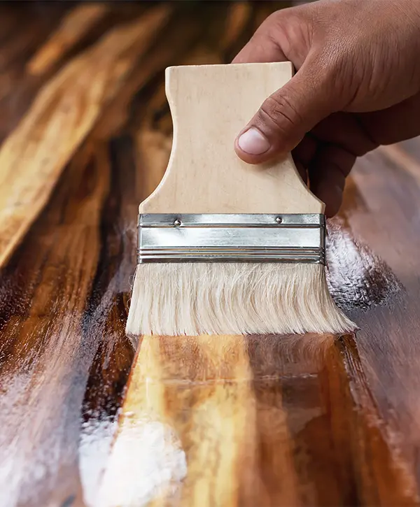 A man sealant a wood floor with a small and fine brush