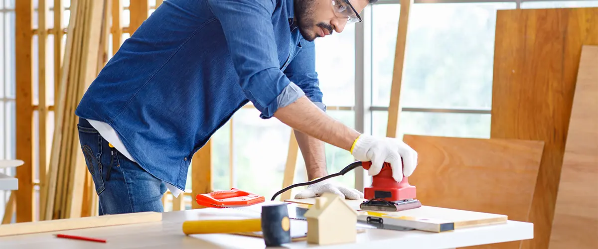 A contractor sanding down a floorboards