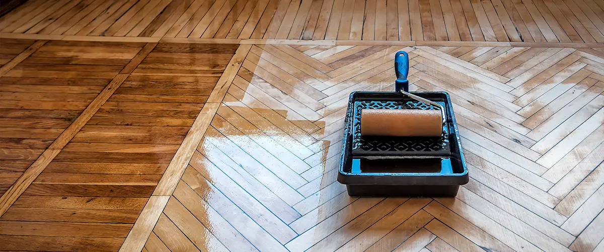 A tray with sealant and fresh seal on a hardwood floor with a herringbone pattern