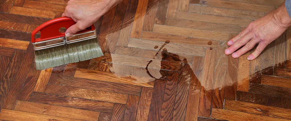 A contractor sealing wood floors with a brush